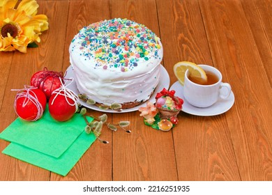 Homemade Easter Cake.White Glaze.bread Pie, Cake. Decorated With Sweets.a White Mug Of Tea. Rose Flowers. On A Rustic Wooden Background. With Easter Red Eggs. Spring Flowers. Happy Easter.meal