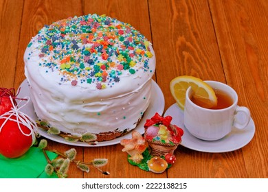 Homemade Easter Cake.White Glaze.bread Pie, Cake. Decorated With Sweets.a White Mug Of Tea. Rose Flowers. On A Rustic Wooden Background. With Easter Red Eggs. Spring Flowers. Happy Easter.meal