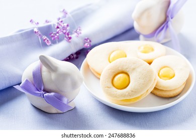 Homemade easter cookies and funny easter bunny on blue pastel background. Easter table setting