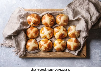 Homemade Easter traditional hot cross buns on wooden tray with textile over gray texture background. Top view, space