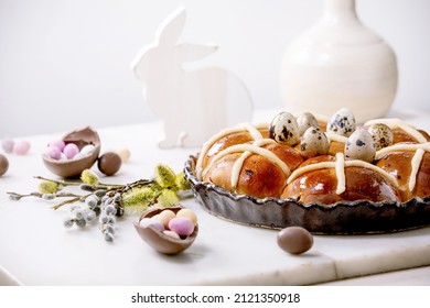 Homemade Easter traditional hot cross buns in ceramic dish with blossom willow branches, chocolate candy and quail eggs on white marble table. Easter holiday baking and decor - Powered by Shutterstock