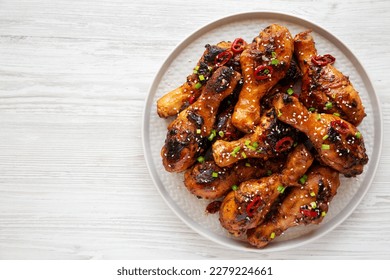 Homemade Easy Sticky Chicken Drumsticks on a Plate on a white wooden background, top view. Overhead, from above, flat lay. Copy space.