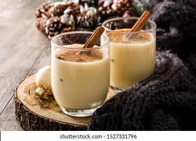 Homemade eggnog with cinnamon in glass on wooden table. Typical Christmas dessert. 