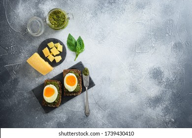 Homemade Eggs Panini Bread With Green Basil Pesto Silver Spoon On Italian Breakfast With Ingredients Green Pesto On Grey And White Concrete Table Surface Overhead Top View Space For Text Lay Flat