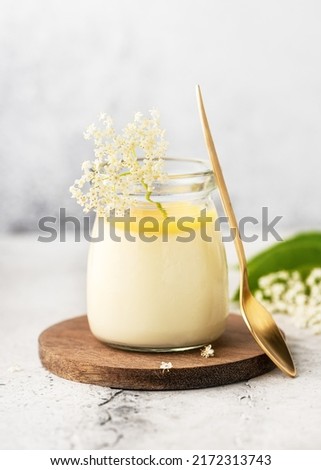Homemade elder flower dessert panna cotta, mousse or pudding in a portion glass jar with lemon curd and fresh flowers. Copy space.