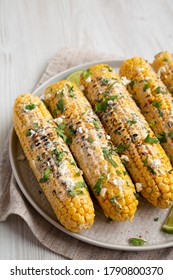Homemade Elote Mexican Street Corn on a plate, side view. 