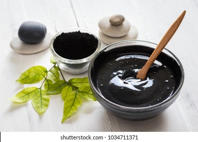 Homemade facial mask and scrub by activated charcoals powder and yogurt on white wooden background