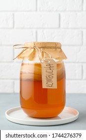 Homemade fermented kombucha tea in a glass jar on a background of a white brick wall. copy space, vertical orientation