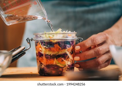 Homemade Fermented Vegetables.Homemade fermented vegetables. Woman pouring water in the jar with vegetables. Vegetable Fermentation Process.