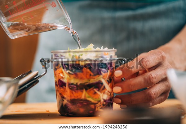 Homemade Fermented Vegetables.\
\
Homemade\
fermented vegetables. Woman pouring water in the jar with\
vegetables. Vegetable Fermentation\
Process.\
\

