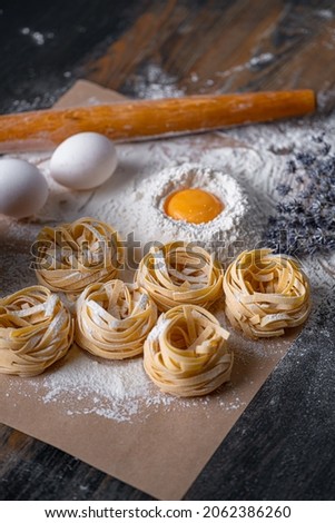 Homemade fettuccine pasta folded in the shape of a nest. Home cooking with ingredients for homemade traditional Italian fettuccine pasta.