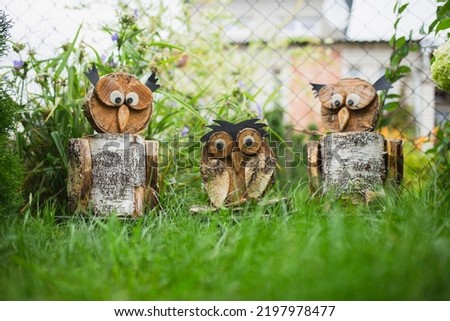 Homemade figurines of an owl from firewood and birch trimmings in a garden on the grass - garden sculptures