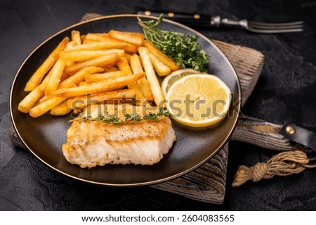Homemade Fish and chips with roast cod whitefish fillet and fried potatoes on plate. black background. top view.