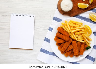 Homemade Fish Sticks And Fries With Tartar Sauce, Blank Notepad On A White Wooden Background, Top View. Flat Lay, Overhead, From Above. 
