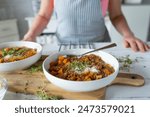 Homemade food. Delicious lentil stew on kitchen counter served by a woman with apron