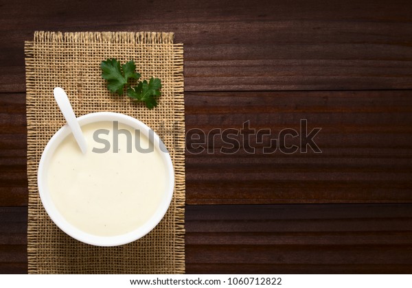 Homemade French Bechamel or White Sauce served\
in sauce boat, photographed overhead on dark wood with natural\
light (Selective Focus, Focus on the\
sauce)