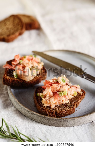 Homemade French dish rilette or pate. Two toasts\
salmon rillettes (pate) on rye bread on plate over beige linen\
tablecloth. Selective\
focus