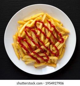 Homemade French Fries With Ketchup, Salt And Pepper On A White Plate On A Black Surface, Top View. Flat Lay, Overhead, From Above.