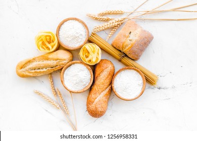 Homemade Fresh Bread And Pasta Near Flour In Bowl And Wheat Ears On White Stone Background Top View