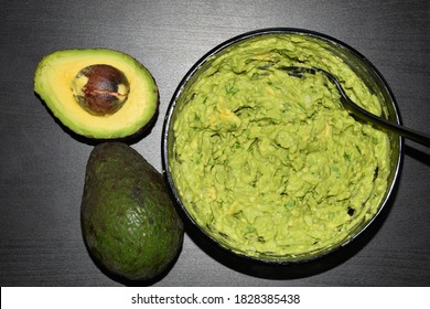 Homemade fresh guacamole with natural avocado, onions, cilantro, serrano peppers chili, and lime juice for breakfast on black table background. Breakfast recipes, traditional homemade sauce. Top view.