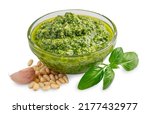 Homemade fresh herbal italian pesto sauce made of blended raw green basil leaves, pine nuts, garlic, parmesan and olive oil served in glass bowl isolated on white background used for pasta or salad