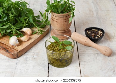 Homemade Fresh Herbal  Italian Pesto Sauce, Green Basil Leaves, Pine Nuts, Garlic, Black Pepper And Olive Oil Served In Glass Bowl On Wooden Background