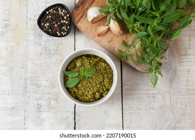 Homemade Fresh Herbal  Italian Pesto Sauce, Green Basil Leaves, Pine Nuts, Garlic, Black Pepper And Olive Oil Served In Bowl On Wooden Background