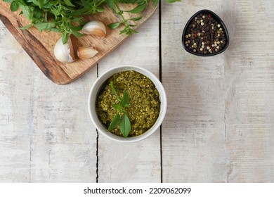 Homemade Fresh Herbal  Italian Pesto Sauce, Green Basil Leaves, Pine Nuts, Garlic, Black Pepper And Olive Oil Served In Bowl On Wooden Background