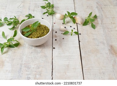 Homemade Fresh Herbal  Italian Pesto Sauce, Green Basil Leaves, Pine Nuts, Garlic, Black Pepper And Olive Oil Served In Bowl On Wooden Background. Copy Space