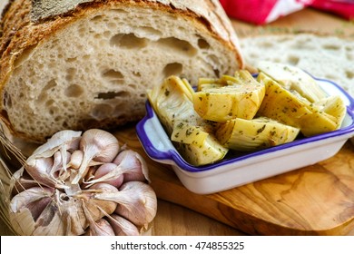 Homemade fresh italian bread and artichokes in brine with spices and herbs on wooden background