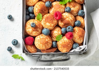 Homemade and fresh poffertjes with fresh berries. Breakfast with mini pancakes and berries.