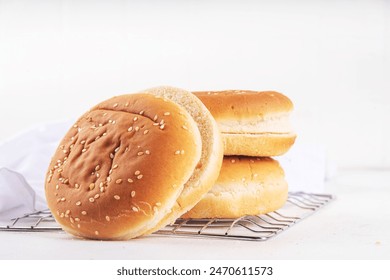 Homemade freshly baked burger buns. Traditional American sesame buns on a white kitchen table - Powered by Shutterstock