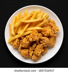 Homemade Fried Chicken Bites And French Fries On A Plate On A Black Surface, Top View. Flat Lay, Overhead, From Above. Close-up.