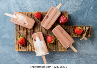 Homemade frozen ice cream chocolate popsicles with strawberry