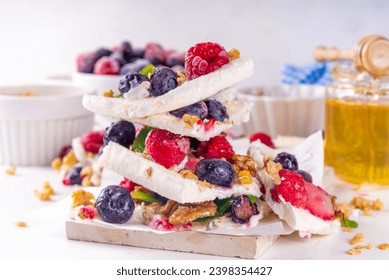 Homemade frozen Yogurt Bark, alternative healthy keto diet ice cream made from greek yogurt, fresh berries, nuts, granola, honey, on baking tray deco. Frozen yoghurt bars with fruit berry toppings - Powered by Shutterstock