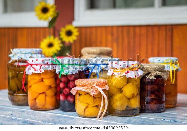 Homemade fruit compote on table, selective\
focus. Organic preserved food in jars. Peach, apricot, cherry,\
apple, pear and plum\
compotes