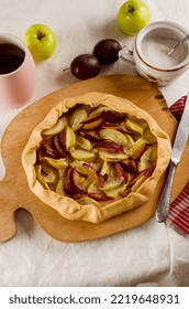 Homemade Galette With Apple And Plum On A White Linen Tablecloth. Open Pie. Top View Of Homemade Pie Crust On The Table. Rustic Home Baked Fruit Pie.
