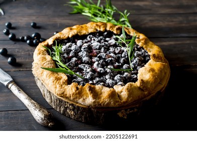 Homemade galette with blackcurrant on old dark wooden  background. Open pie. Top view of homemade pie crust on the table. rustic home baked fruit pie.