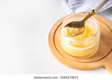 Homemade ghee butter in small glass jar on white kitchen table background, copy space. Melted organic ghee clarified butter, Bio Ayurveda Lactose free high quality animal fat source