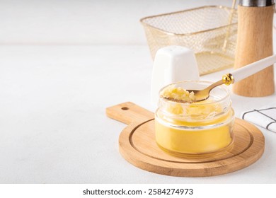 Homemade ghee butter in small glass jar on white kitchen table background, copy space. Melted organic ghee clarified butter, Bio Ayurveda Lactose free high quality animal fat source