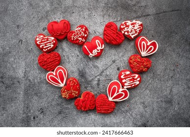 Homemade ginger cookies in the shape of a heart in red icing sugar. Delicious ginger cookies heart on a gray concrete background. Freshly baked gingerbread cookies for Valentine's Day.