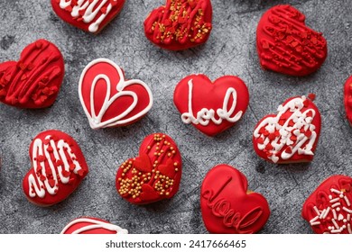 Homemade ginger cookies in the shape of a heart in red icing sugar. Delicious ginger cookies heart on a gray concrete background. Freshly baked gingerbread cookies for Valentine's Day.