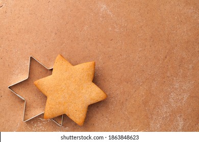 Homemade gingerbread cookie star and cookie cutter on raw gingerbread dough. Empty room for text. Top view