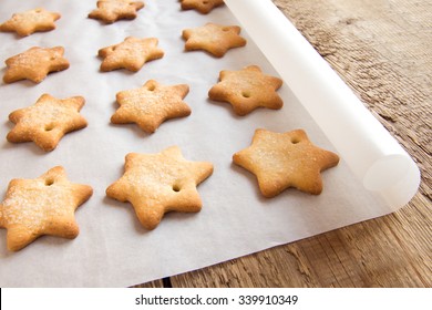 Homemade gingerbread cookies (stars) on baking paper and rustic wooden table