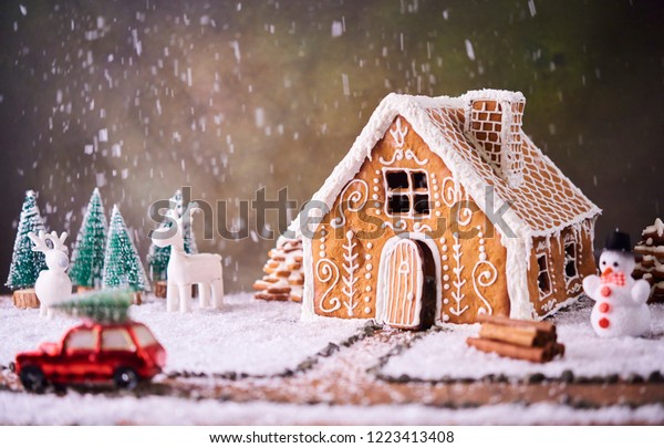Homemade gingerbread house. Christmas concept.\
gingerbread house, cookies, tiny car toy with tree and deer with\
christmas tree at\
background