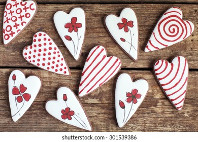 Homemade gingerbreads in the shape of heart with burgundy and white frosting, flowers patterns on the wooden table. Space for text and selective focus. - Powered by Shutterstock