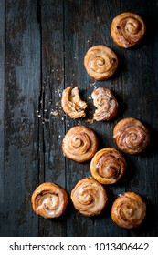 Homemade glazed puff pastry cinnamon rolls with custard and raisins over old dark blue wooden background. Top view, space. Rustic style