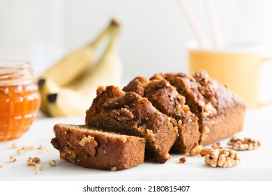 Homemade gluten free banana bread with walnuts and honey cut into appetizing slices on white marble table, closeup view