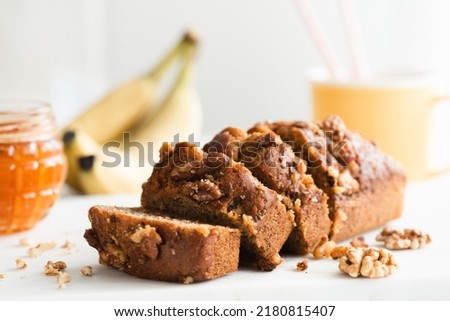 Homemade gluten free banana bread with walnuts and honey cut into appetizing slices on white marble table, closeup view