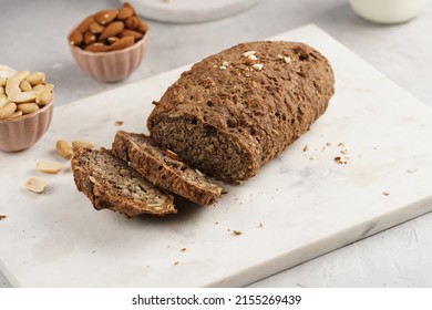 Homemade gluten-free and yeast-free buckwheat whole bread bread loaf with sunflower and pumkin seeds and nuts, cut in slices on white marble board - Shutterstock ID 2155269439